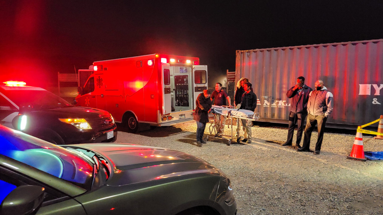 Ambulance, police cars, and film crew staging an emergency scene at night in Los Angeles